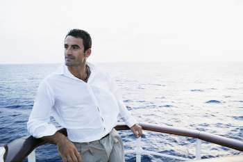 Mid adult man leaning against the railing of a ship