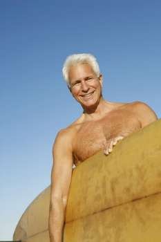 Portrait of a mature man holding a surfboard under his arm
