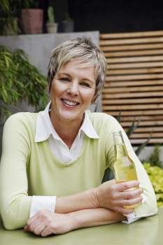 Portrait of a mature woman holding a bottle of wine and smiling