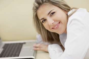 Portrait of a mid adult woman in front of a laptop and smiling