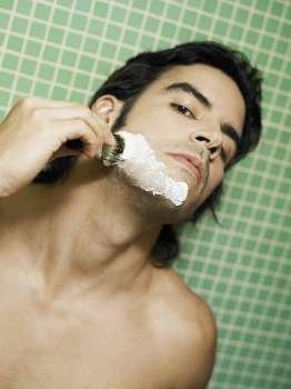 Portrait of a young man applying shaving cream on his face
