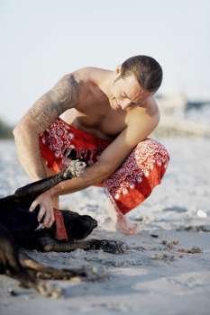 Mid adult man stroking a dog on the beach