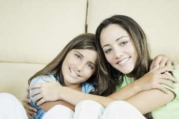 Portrait of a young woman and a teenage girl hugging each other and smiling