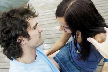 High angle view of a young couple sitting at a pier and looking at each other