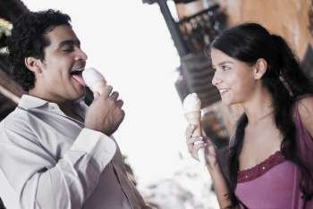 Side profile of a young man licking an ice-cream with teenage girl looking at him