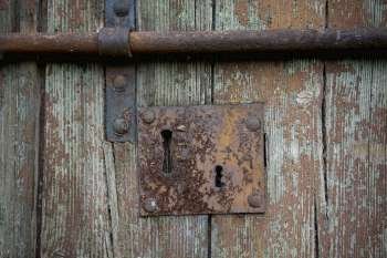 Close-up of a keyhole and a rusty latch on a wooden door