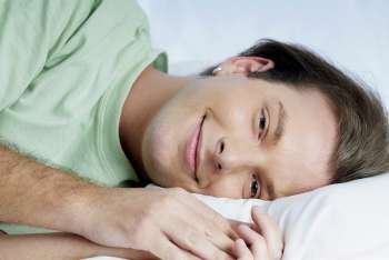 Portrait of a young man lying on the bed and grinning