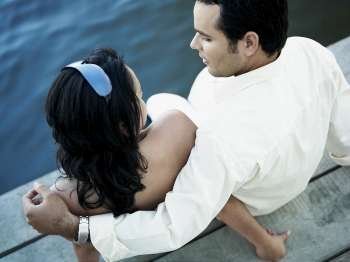 High angle view of a young couple sitting on a pier
