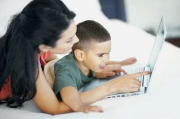 Side profile of a young woman teaching his son to use a laptop