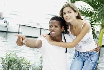 Close-up of a young man pointing forward with his arm around a young woman