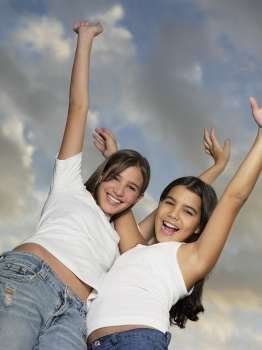 Low angle view of a teenage girl and her sister standing with her arms outstretched
