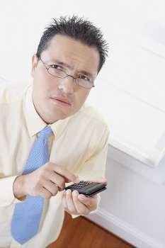 High angle view of a businessman using a calculator and thinking
