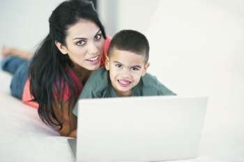 Portrait of a boy and his mother smiling in front of a laptop