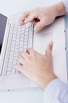 Close-up of a person´s hands working on a laptop and crossing his finger