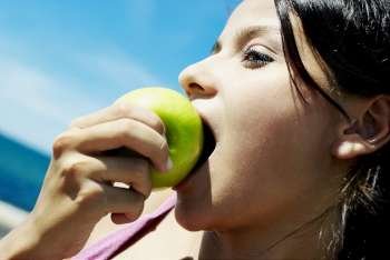 Close-up of a teenage girl eating a green apple