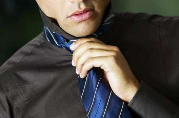 Mid section view of a businessman adjusting his tie