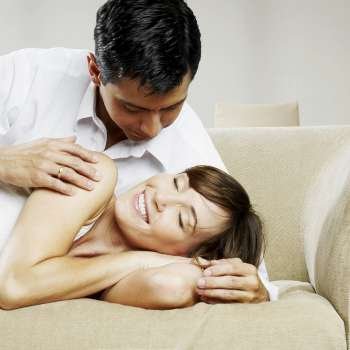 Mid adult man looking at a young woman lying on a couch
