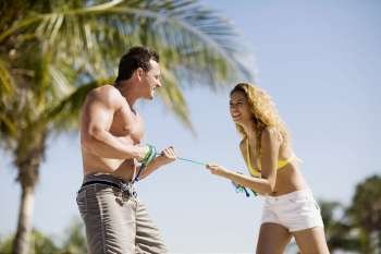 Young couple standing on the beach and pulling a rope