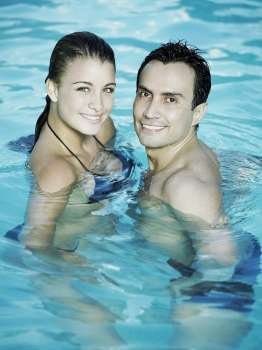 Portrait of a young couple standing in the swimming pool