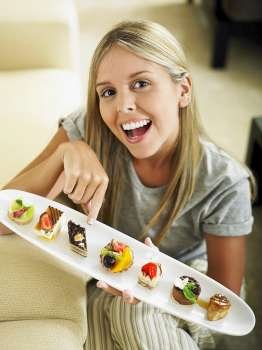 Portrait of a young woman holding a platter of pastries
