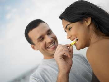 Close-up of a young man feeding a young woman a slice of fruit