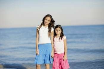 Portrait of a girl and her sister standing on the beach