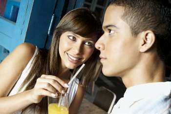 Close-up of a young woman offering a glass of juice to a young man