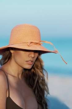 Close-up of a young woman wearing a hat on the beach