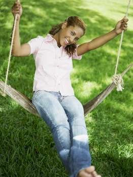 Portrait of a young woman swinging on a swing