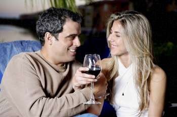 Close-up of a mid adult man and a mid adult woman holding glasses of red wine and smiling