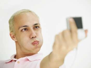 Close-up of a young man making a face and taking a self portrait with a digital camera