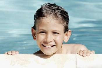 Boy leaning at the poolside and smiling