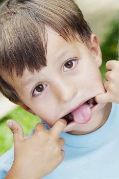Close-up of a boy stretching his mouth with his fingers