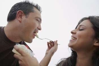 Close-up of a young woman feeding ice-cream to a mid adult man