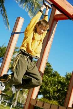 Low angle view of a boy hanging on a jungle gym