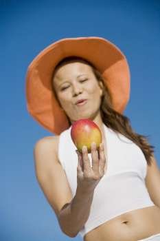 Low angle view of a young woman holding an apple