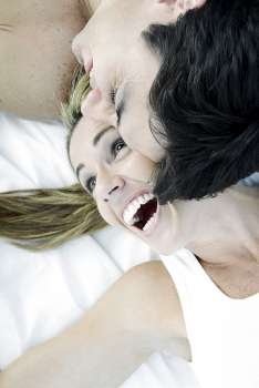 High angle view of a mid adult couple lying on the bed and smiling