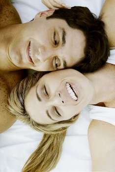 High angle view of a mid adult couple lying on the bed and smiling