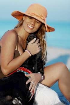 Close-up of a young woman sitting with a dog on the beach