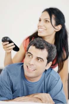 Close-up of a young woman and a mid adult man watching television and smiling