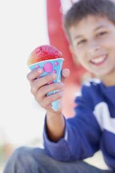 Portrait of a teenage boy smiling and holding an ice-cream cone