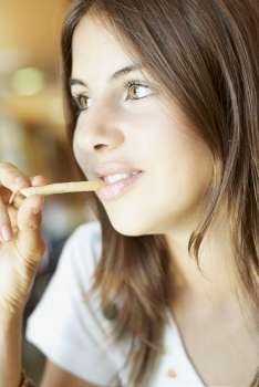 Close-up of a young woman eating French fries and smiling