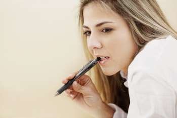 Side profile of a mid adult woman holding a pen and thinking