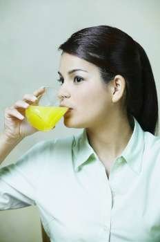 Close-up of a young woman drinking a glass of orange juice