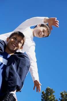 Low angle view of a teenage boy carrying his brother on his shoulders