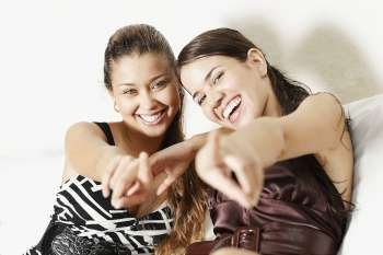 Portrait of two young women smiling and pointing forward