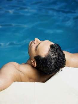 High angle view of a mature man leaning at the poolside and looking up