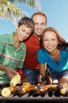 Portrait of a mid adult couple with their son in front of a barbecue grill