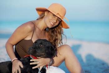 Portrait of a young woman stroking a dog on the beach