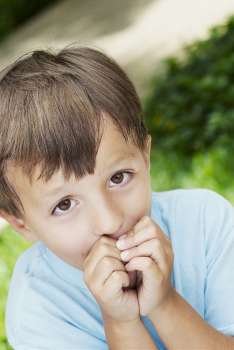 Close-up of a boy with his hands covering his mouth